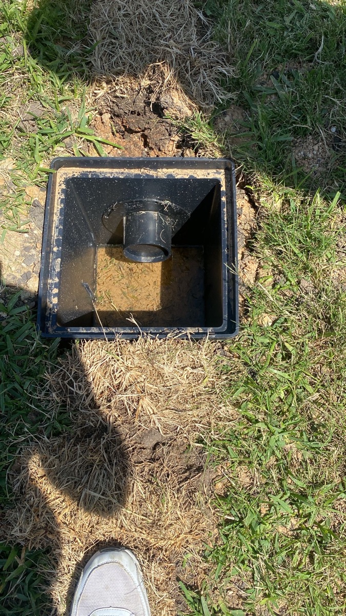 Checking drainage pipe slope with a level during a French drain repair in Houston TX