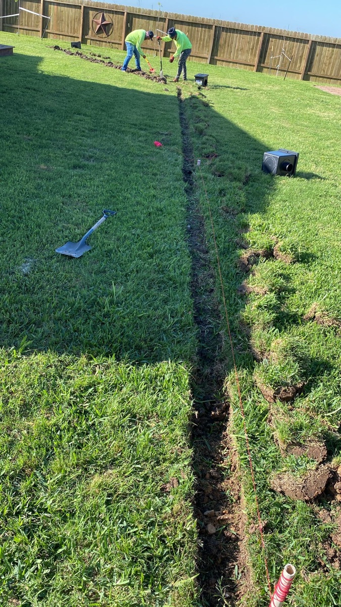 Crew digging a French drain trench to fix standing water in a Houston backyard